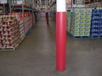 A warehouse aisle with stacked goods and a red-and-white striped pillar.